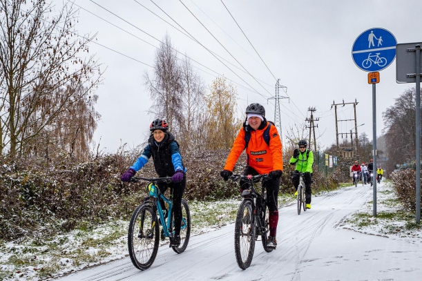 Rowerzyści na rowerach, w tle zimpowe warunki. 