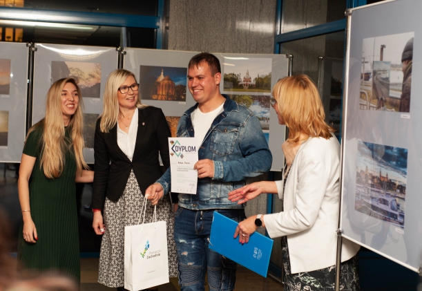 Wernisaż wystawy "Otwarte Pomorze Zachodnie. Oczami Imigrantów" w Książnicy Pomorskiej w Szczecinie. Członkini Zarząd Województwa Zachodniopomorskiego Anna Bańkowska rozmawia z trzema osobami - organizatorami wystawy i autorami zdjęć.