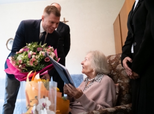 Dyrektor Kordela wręcza bukiet kwiatów jubilatce Krystynie Bogdanowicz. 